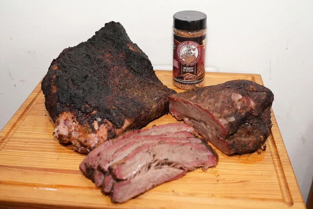 Smoked brisket and sliced meat on a wooden cutting board beside a Gregory's Brand seasoning jar.