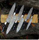 A 13" handmade Damascus steel chef knife by Texan Knives, featuring an epoxy resin handle and leather sheath, is displayed outdoors on tree bark—perfect for kitchen pros seeking premium knife sets.