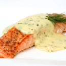 A cooked salmon fillet topped with creamy herb sauce and garnished with a sprig of fresh dill, expertly seasoned to perfection using The Spice Lab Seafood Seasoning Set by The Spice Lab, served on a white plate.