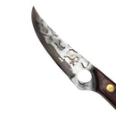 A close-up of the Spaceman Knives Meteor Series Boning Knife showcases its patterned blade and wooden handle with a brass rivet, resting on marble next to a black leather case—ideal for precise kitchen prep.