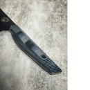 Close-up of a Spaceman Knives Dark Matter Kiritsuke handle with a textured, layered black and gray pattern on a mottled gray surface. The partially visible 7CR17MOV-X steel blade and a round logo near the top left complete the look.