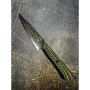 The Spaceman Knives Gravity Series Utility Knife features a striking Damascus-patterned pointed blade and a green-and-black textured handle, displayed on a gritty, speckled dark surface.