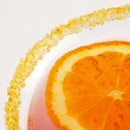 Close-up of a drink in a glass rimmed with The Spice Lab Zesty Orange Sugar Cocktail Rimmer and topped with an orange slice floating on the pink liquid, creating the perfect citrus cocktail garnish.