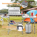 Create the perfect camping cook station with the DirectDeals Foldable Outdoor BBQ Portable Grilling Table With Windscreen Bag—includes shelves, propane tank space, and a steel windscreen. Tent and trees complete the outdoor vibe.