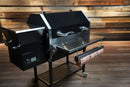 Black Recteq RT-590 pellet grill featuring a Pimp My Grill® Tactical Stainless Folding Front Shelf and a side-mounted paper towel holder.