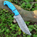 The Texan Knives Custom Handmade Damascus Steel Hunting Knife, featuring a 10-inch patterned blade and resin handle, is displayed on a tree branch with green foliage in the blurred background. Includes leather sheath.