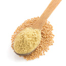 A wooden spoon filled with The Spice Lab Ground Yellow Mustard 1 lb rests atop a bed of whole mustard seeds, all set against a white background—an eye-catching presentation ideal for foodservice spice racks or enhancing your signature BBQ seasoning with The Spice Lab quality.