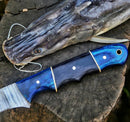 A close-up of the Texan Knives Custom Handmade Damascus Boning Knife – 13" Pakkawood Handle with a patterned blade rests on wood beside a freshly caught, mouth-hooked catfish.
