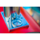 A close-up of a round thermometer gauge mounted on the vivid red and silver exterior of the WPPO Le Peppe Portable Wood-Fired Pizza Oven by WPPO LLC Direct, with the needle indicating just above 100°F. The softly blurred blue and yellow background highlights this stylish outdoor pizza oven in action.