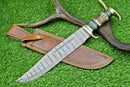 A Texan Knives Custom Handmade Damascus Steel Bowie Knife with a 16" blade and stag horn handle rests on green grass beside its leather sheath and deer antlers.