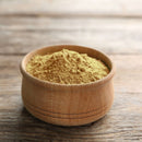 A small wooden bowl filled with The Spice Lab Ground Oregano, a light brown powdered spice and an essential Mediterranean herb from The Spice Lab, sits on a rustic wooden surface.