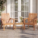 Two wooden chairs and the 17″ Square Acacia Wood Side Table with Slatted Top by DirectDeals sit on a porch with flowers and a book, creating a cozy, plant-filled outdoor seating area in front of glass doors.