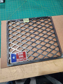 a metal grate with a sticker on it, placed on a wooden surface.