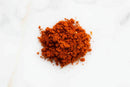A small pile of World Spice KC Tailgater's BBQ Rub is on a white surface.
