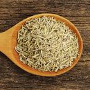 A wooden spoon filled with The Spice Lab Cut & Sifted Rosemary rests on a rustic wooden surface, capturing the essence of this classic Mediterranean herb from The Spice Lab.