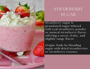 A glass of pink strawberry mousse topped with whipped cream and fresh strawberries sits on a pink plate next to a cut strawberry, finished with a sprinkle of Spice Wheel Strawberry Sugar by Spice Wheel for an extra burst of sweetness.