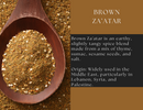 A wooden spoon holds a mound of Spice Wheel Brown Za’atar, set against a backdrop of scattered spices. Text highlights its earthy flavor, aromatic thyme notes, and authentic Middle Eastern origins—especially from Lebanon, Syria, and Palestine.