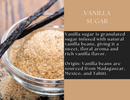 A glass bowl of Spice Wheel Vanilla Sugar is placed beside natural vanilla beans on a wooden surface. Text highlights Spice Wheel Vanilla Sugar’s rich vanilla flavor and origins, set against a tan and black color scheme.