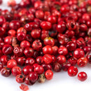 A close-up of a pile of The Spice Lab Pink Pepper Berries (Whole) Brazilian Pink Peppercorns on a white background.