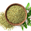 A wooden bowl filled with The Spice Lab Organic Oregano Leaf, some oregano leaf scattered beside it, and fresh oregano sprigs on a white background—a must-have from The Spice Lab for Mediterranean cooking.