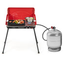 The DirectDeals 2-in-1 Gas Camping Grill and Stove with a red and black design is a versatile portable cooking station, shown grilling meat, shrimp, veggies, and boiling water with a silver propane tank attached.