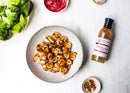 A plate of grilled shrimp, a bottle of Terrapin Ridge Farms Tropical Tequila Sauce—the perfect seafood sauce—lettuce, pickled onions, and spices are arranged on a white surface.