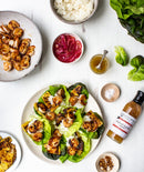 Overhead view of lettuce wraps with grilled shrimp, pineapple, and cabbage, surrounded by rice, pickled onions, shrimp, dressing, spices, and a bottle of Terrapin Ridge Farms Tropical Tequila sauce.