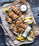 Golden-brown fried fish fillets with lemon wedges are served on parchment as a bottle of Terrapin Ridge Farms Jalapeno Aioli Squeeze Garnishing Sauce sits nearby, ready to add a creamy, zesty finish.