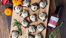 A wooden board holds dark bread squares topped with creamy chicken salad and rosemary. Mini pumpkins, autumn leaves, and Terrapin Ridge Farms Tart Cherry, Apple and Rosemary Glaze create a festive scene for Holiday Entertaining.