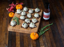 A wooden board holds crackers topped with chicken salad and Terrapin Ridge Farms Tart Cherry, Apple and Rosemary Glaze, surrounded by pumpkins, rosemary sprigs, a Terrapin Ridge Farms sauce bottle, and red autumn leaves for festive entertaining.