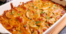 A baked dish of scalloped potatoes in a white casserole, topped with golden-brown cheese and parsley, paired with Terrapin Ridge Farms’ Garlic Kraut Mustard for a tangy flavor boost.