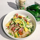 A bowl of rice topped with diced raw fish, avocado, pineapple, cherry tomatoes, cucumber, green onions, and a drizzle of Terrapin Ridge Farms Jalapeno Aioli Squeeze Garnishing Sauce. Jalapeños and a Terrapin Ridge Farms aioli bottle are in the background.
