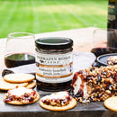 Terrapin Ridge Farms Blueberry Bourbon Pecan Jam - 2oz is served with crackers, cheese, a nut-coated cheese log, and red wine—an elegant addition by Terrapin Ridge Farms to any outdoor charcuterie board spread.