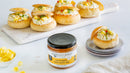 A jar of Terrapin Ridge Farms Pineapple Habanero Dip is displayed with bread rolls stuffed with the sweet and spicy spread and pineapple chunks, all arranged on a white marble tray with extra pineapple pieces scattered around.