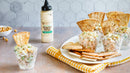 Individual cups of creamy pasta salad with pita wedges sit beside pita bread, a bowl of chickpeas, and a bottle of Terrapin Ridge Farms Avo Aioli Roasted Garlic Squeeze. A yellow checkered napkin completes the scene.