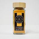 A glass jar with a bamboo lid labeled "Spice Wheel Turmeric Powder" by Spice Wheel, Net Wt. 71g, filled with vibrant yellow turmeric powder that brings warmth and flavor to your favorite dishes.