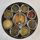 The Spice Wheel Italian Spice Wheel by Spice Wheel is a round metal spice organizer featuring nine separate compartments, each containing a distinct Italian herb or spice. Viewed from above, the central section holds a reddish-brown spice blend with an included spoon for easy serving. This elegant and practical kitchen gift is perfect for any culinary enthusiast.
