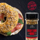 A seeded bagel with smoked salmon and greens sits beside a jar of Everything + More seasoning from The Spice Lab Taste of America Seasoning Collection. A red stamp reads “Perfect for all-around cooking” on a dark background, highlighting the versatility of these American-inspired spice blends by The Spice Lab.