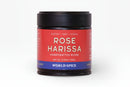 A jar of World Spice Rose Harissa, a handcrafted blend featuring earthy heat with citrus and floral notes, net weight 2.05 oz (58g), from World Spice, displayed against a white background and inspired by Ottolenghi.