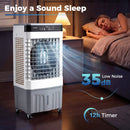 A woman sleeps next to a DirectDeals Evaporative Air Cooler 2100 CFM with 5.3 Gal Tank emitting blue airflow, with text: Enjoy a Sound Sleep, 35 dB Low Noise, and 12h Timer. A lamp softly lights the dim room.