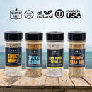Introducing The Spice Lab Seafood Seasoning Collection by The Spice Lab—four gourmet blends: Smoky Maple, Spicy Seafood, Lemon Pepper + Thyme, and Shrimp + Crab Boil, artfully arranged on a wooden surface with the sea as a backdrop. Each blend is gluten free, non-GMO, all natural, and made in the USA. This premium collection is perfect for seasoning everything from classic shrimp and crab boils to creating the ultimate salmon dish.