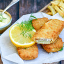 Breaded fish fillets with a lemon slice and dill garnish on parchment paper, enhanced with The Spice Lab Seafood Seasoning Collection by The Spice Lab, served alongside fries and a bowl of dipping sauce in the background.