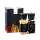 The Spice Lab Himalayan Pink Salt & Premium Black Pepper Grinder Set features two elegantly labeled spice jars displayed before a sleek black box adorned with vibrant spice graphics, all proudly branded by The Spice Lab—an essential set that adds gourmet flavor and sophisticated style to your kitchen.