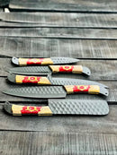 Four Texan Knives 13" Stainless Steel forged blades with olivewood & epoxy handles are displayed on a rustic surface. This knife set includes hammered blade patterns and comes with a leather sheath.