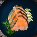 Sliced gravlax arranged on a dark plate with fresh dill and lemon wedges, perfectly complemented by a sprinkle of The Spice Lab Seafood Seasoning Set from The Spice Lab.