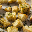 Close-up of homemade croutons sprinkled with The Spice Lab Organic Parsley Flakes and black pepper on a parchment-lined baking tray.