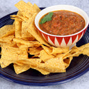 A blue plate with yellow corn tortilla chips and a bowl of chunky red salsa garnished with cilantro, finished with a sprinkle of The Spice Lab Scotch Bonnet Sea Salt by The Spice Lab for a spicy Caribbean-inspired flavor.