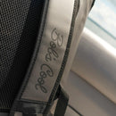 Close-up of a gray and black strap on the Bob The Cooler Co. 25L "The Bro" Backpack Soft Cooler, featuring the brand name “Bob - The Cooler Co.” in script. The background is blurred, with part of a car seat and a hint of sky visible.