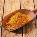 A wooden scoop filled with The Spice Lab Indian Curry Seasoning Spice Maharaja Style rests on a rustic wooden surface, promising a rich and authentic curry flavor in every dish.