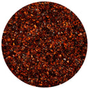 Close-up of The Spice Lab Korean Red Chili Pepper Flakes (Gochugaru) filling a circular frame, showcasing a vibrant blend of deep red, orange, and brown hues with small, irregularly shaped flakes.